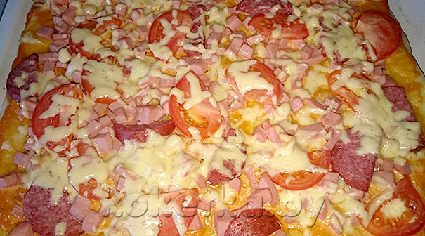 готовая к употреблению домашняя пицца с помидорами и колбасой