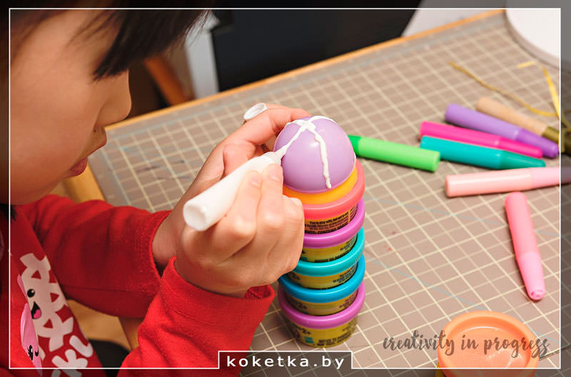 Девочка рисует на пасхальном яйце